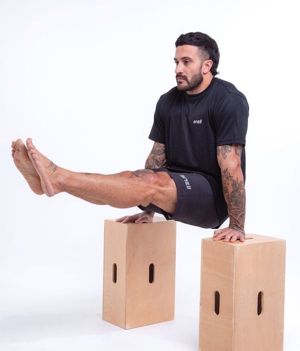 Man performing a controlled strength exercise in a modern, dark gym.